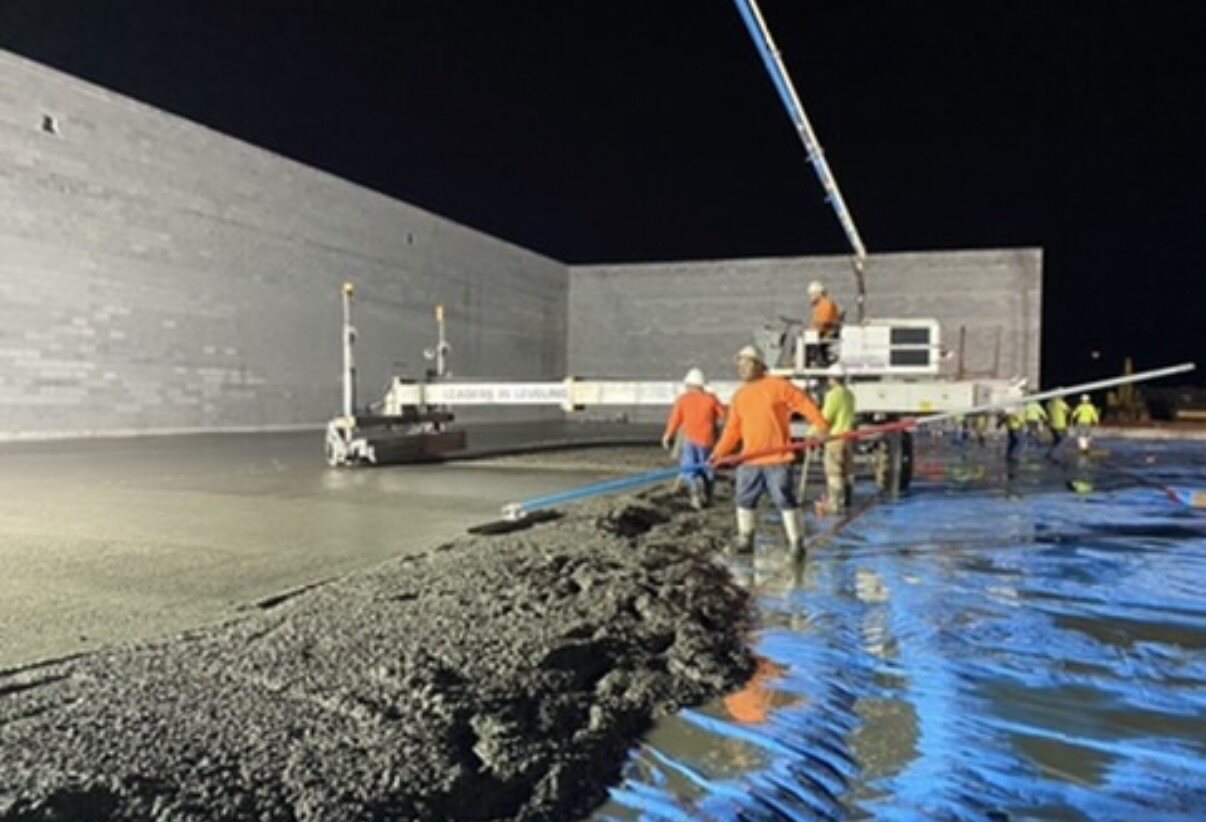 Laser screed cutting a fresh slab to grade on a night pour
